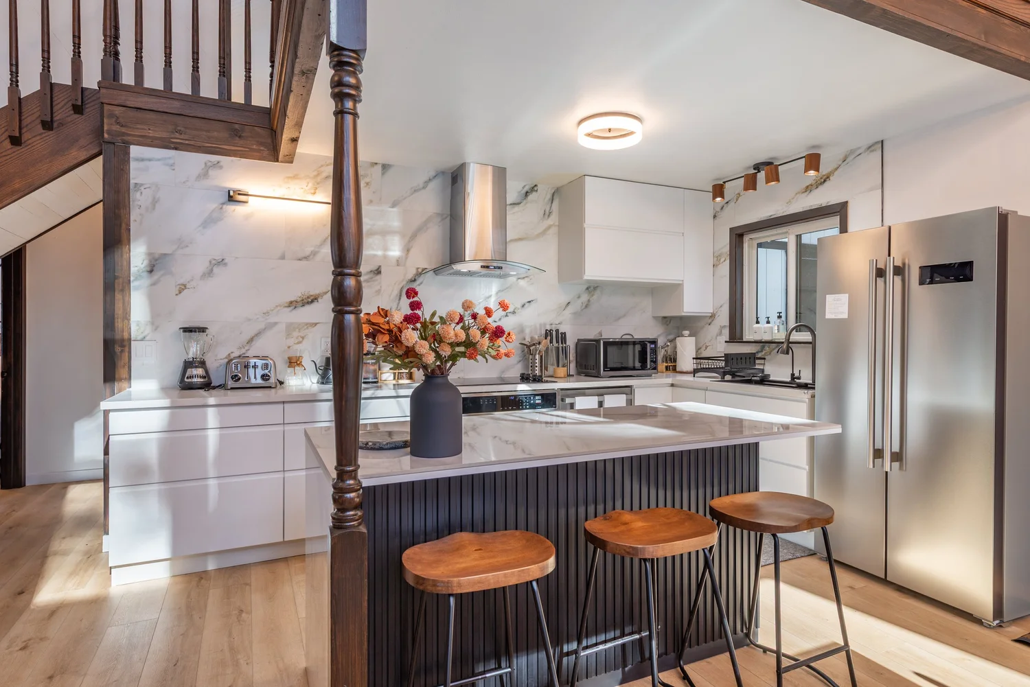 Renovated kitchen with marble backsplash, fluted island and walnut bar stools