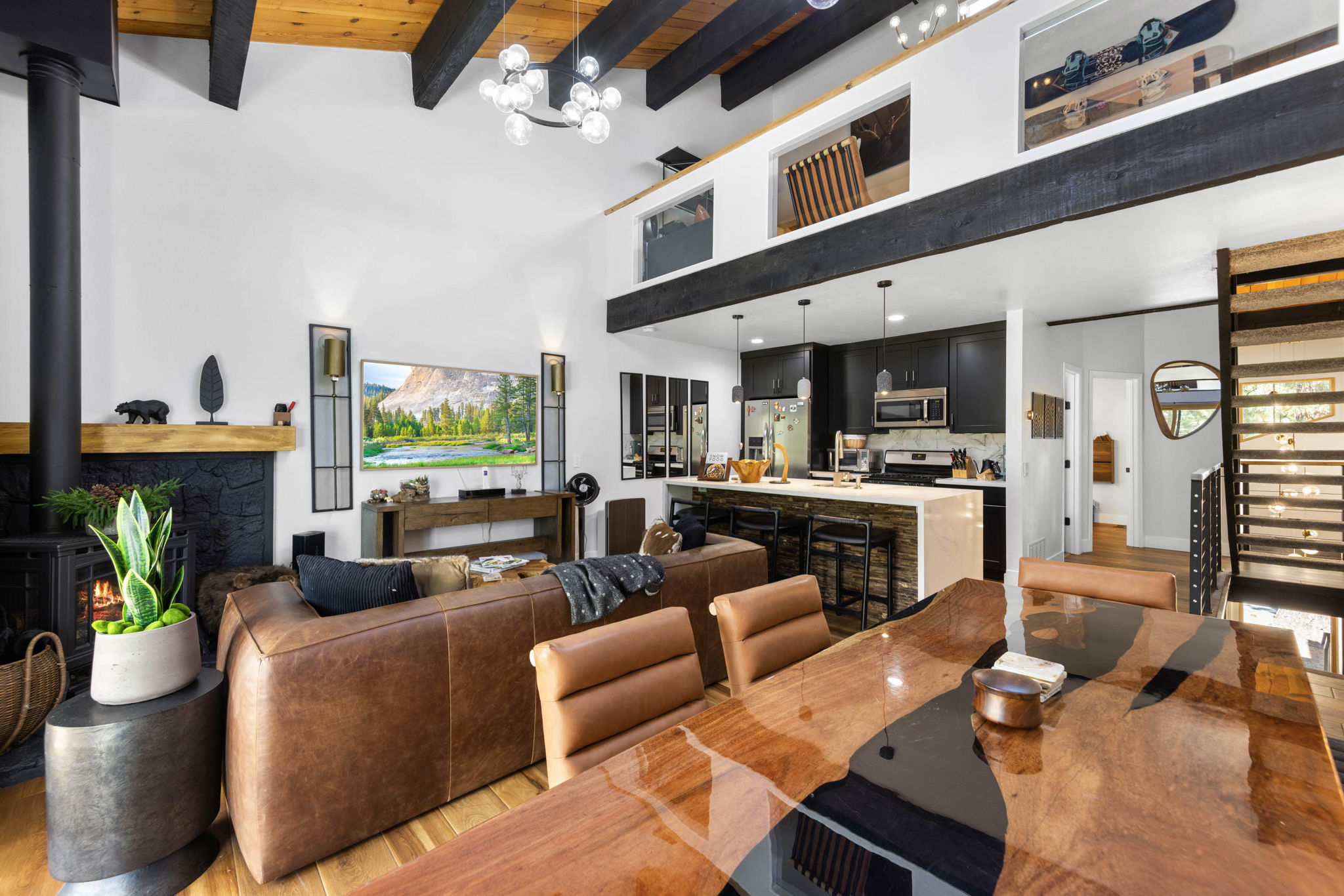 Cubs Manor great room después de la renovación, black kitchen and loft under blackened beams